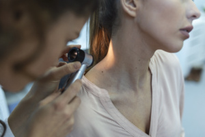 Examen dermatologique du cou avec dermatoscope.